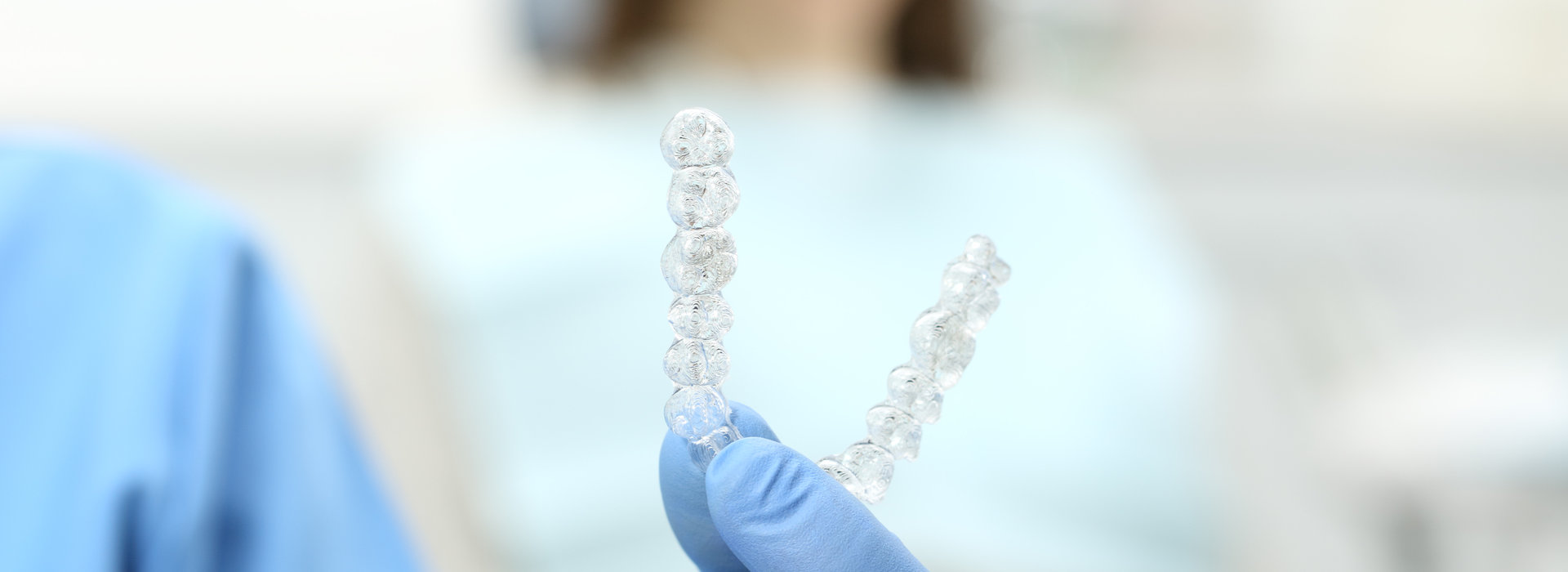 A dentist is holding a Invisalign braces.